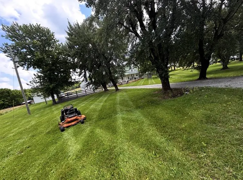 Zero-turn mower on a shaded lawn with clean stripes